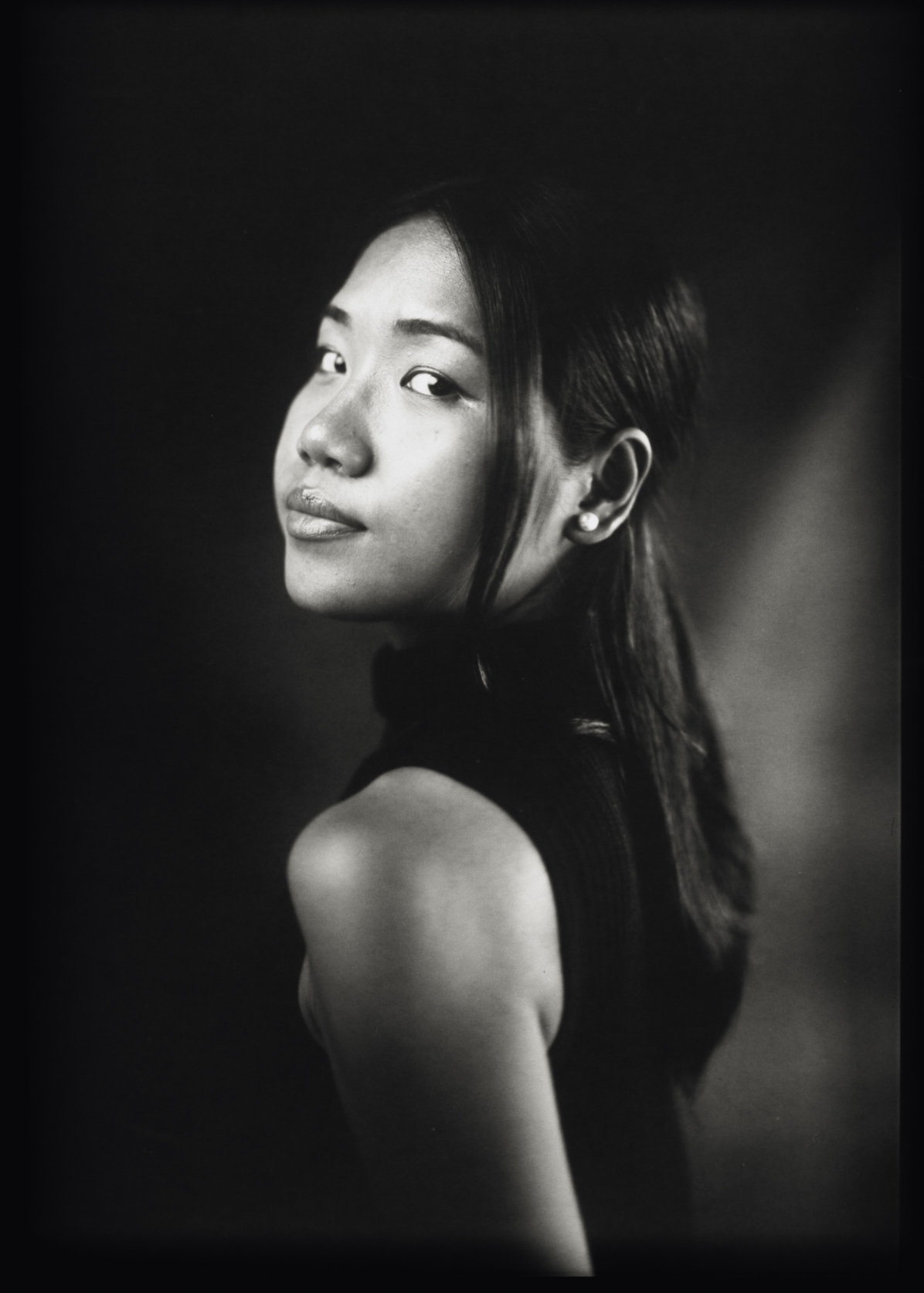 Black and white 5×7 large format profile portrait of a woman turning towards the camera in low key lighting